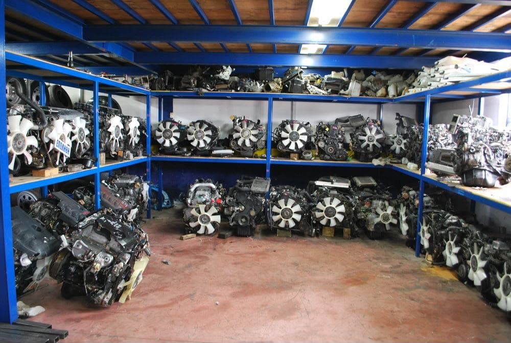 Blue steel shelving holding truck and SUV engines with cooling fans attached